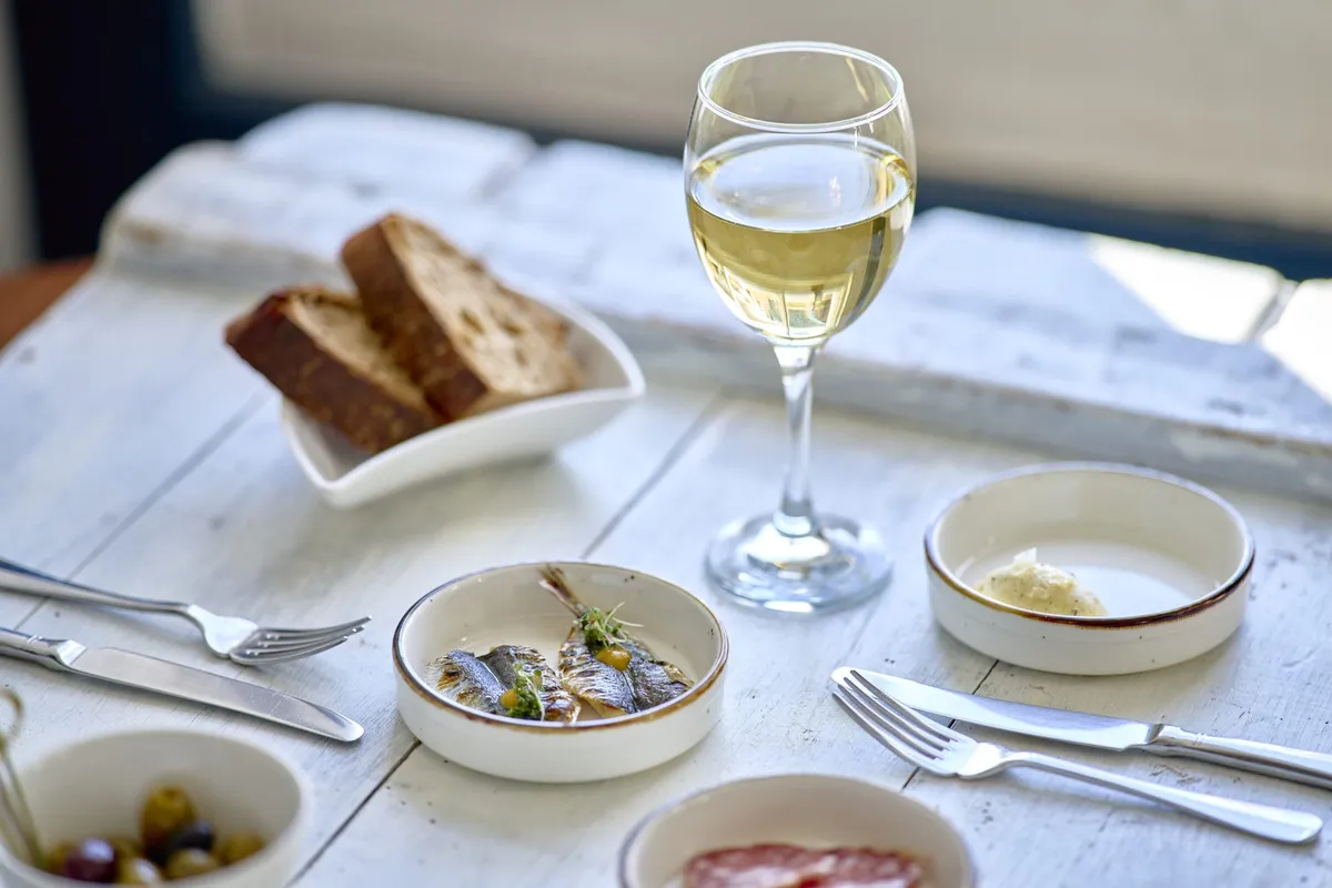 A row of small plates with a glass of white wine