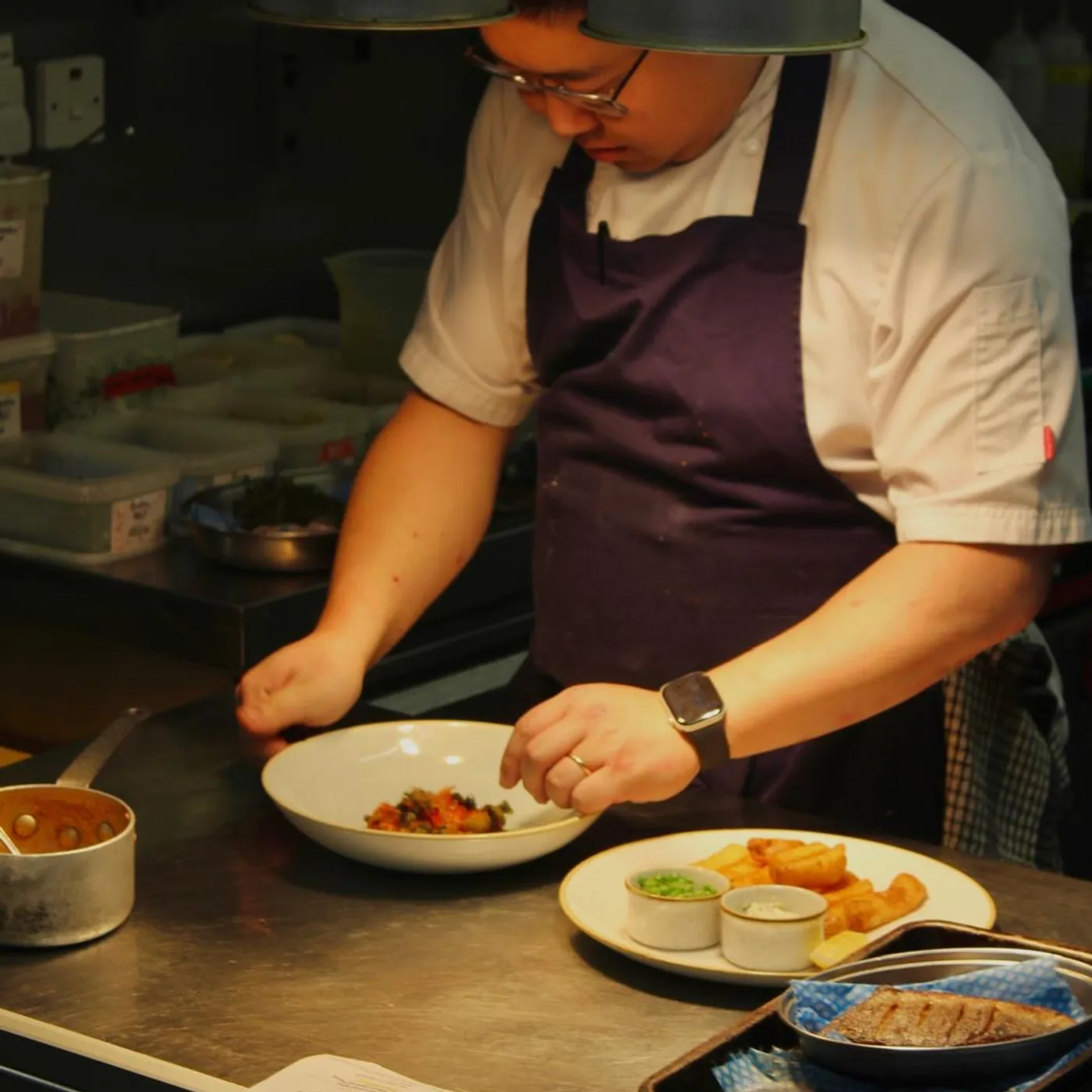 Han Wang plating a dish at the pass