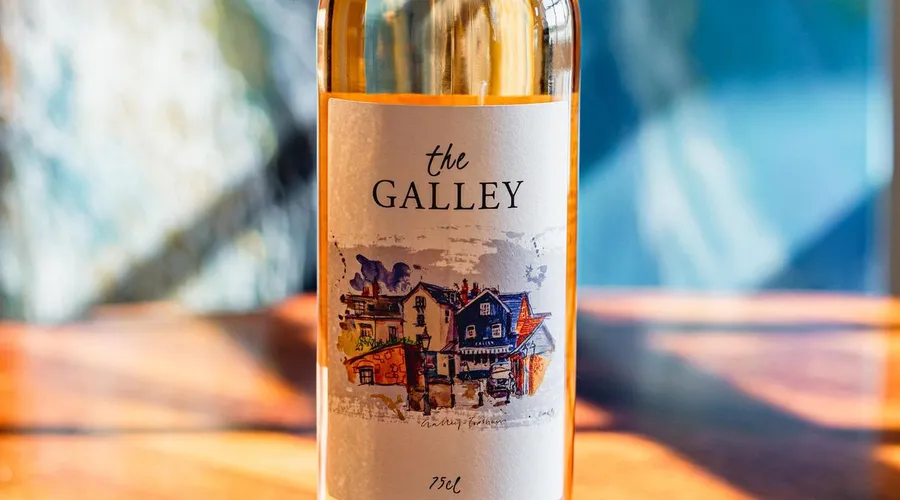 A bottle of The Galley rosé wine with its watercolour Topsham label, lit by the sun